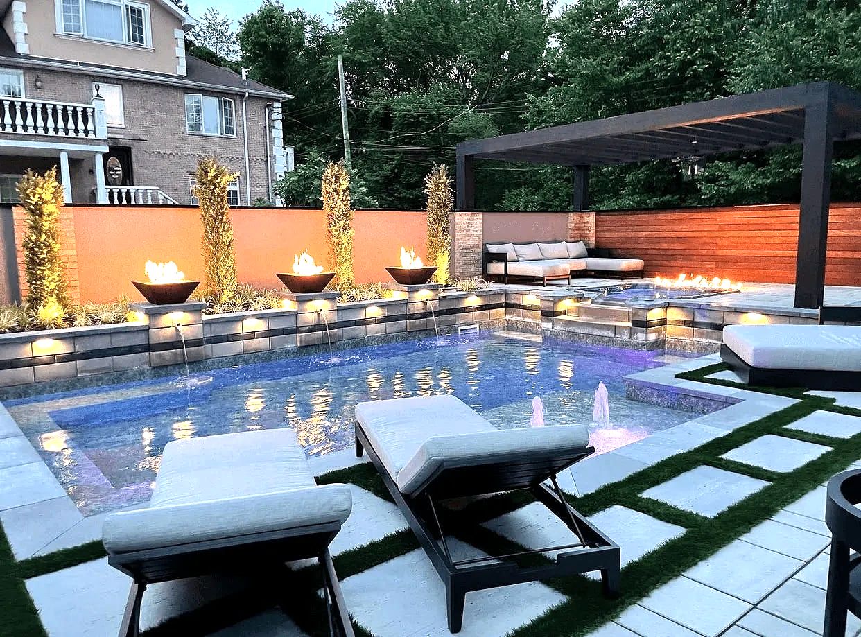 Dusk backyard pool with fire bowls, pergola, lounge chairs, pavers